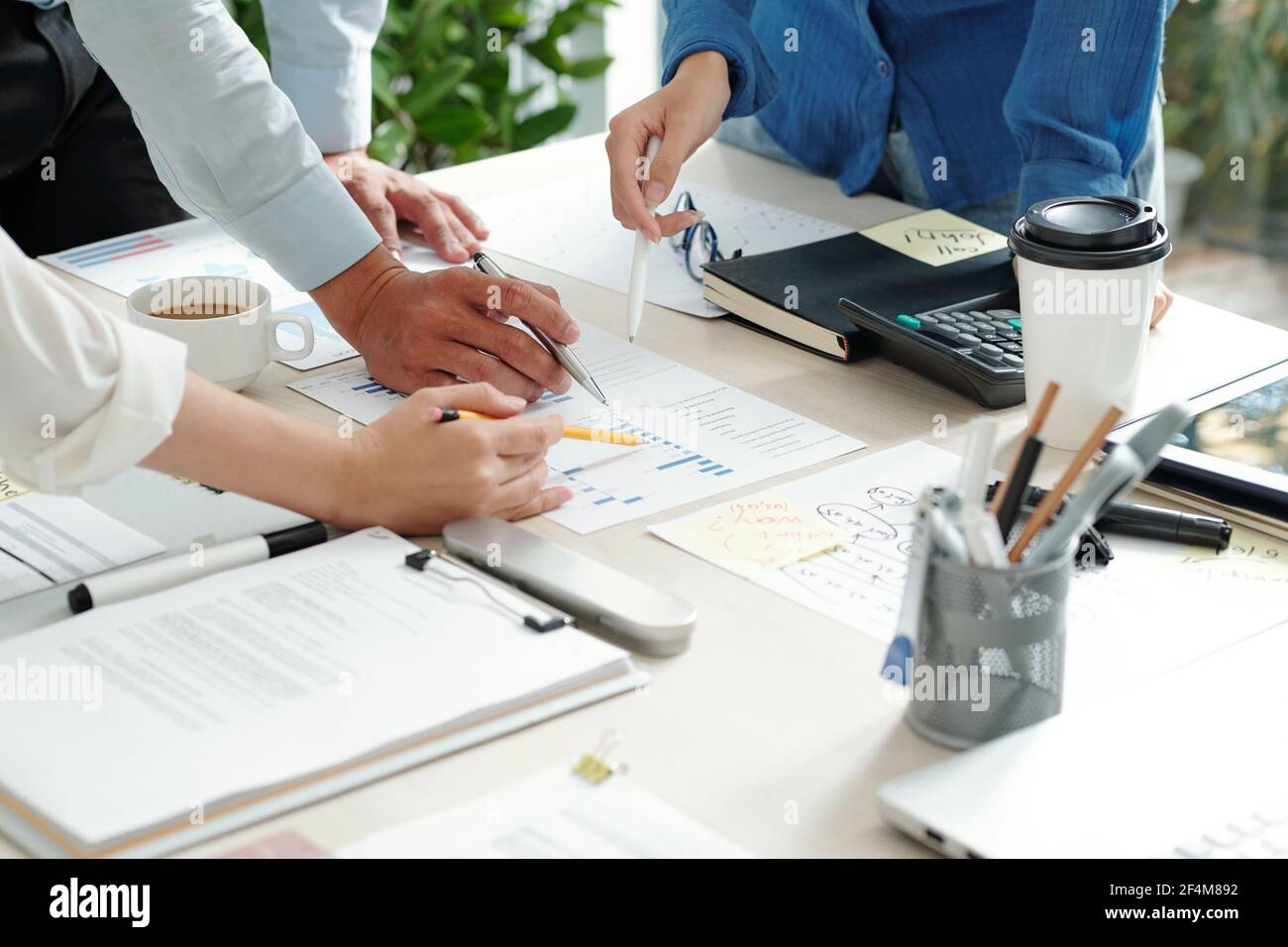 Groupe de responsables pointant vers le tableau sur la table du bureau quand discuter des statistiques de vente Banque D'Images