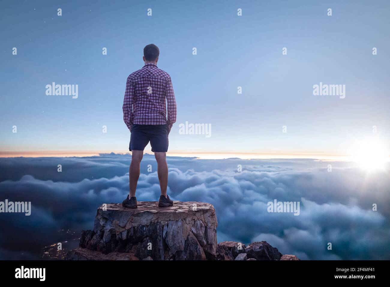 Homme sur un sommet de montagne appréciant la vue sur le nuages Banque D'Images