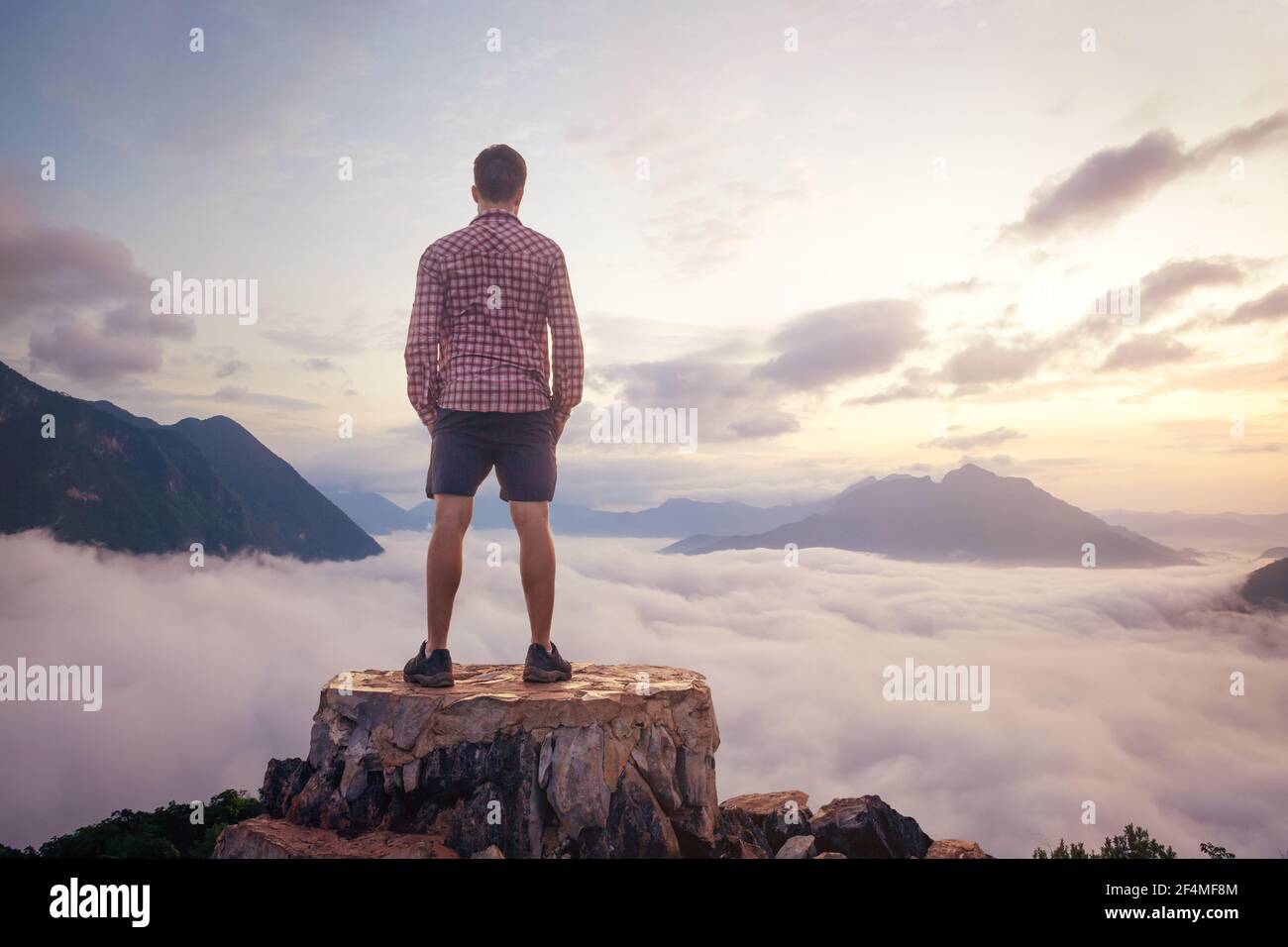 Homme debout sur un sommet de montagne au-dessus des nuages Banque D'Images