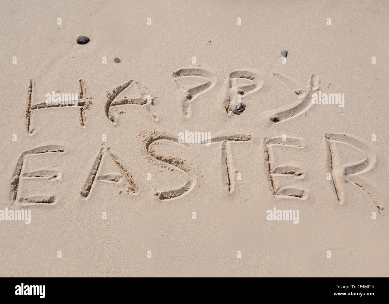 Joyeuses Pâques écrites dans le sable sur une plage de Norfolk. Banque D'Images