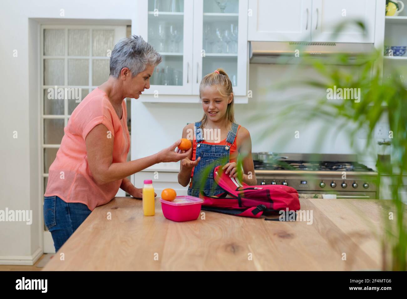 Grand-mère caucasienne senior donnant à la petite-fille un panier repas et des fruits cuisine Banque D'Images