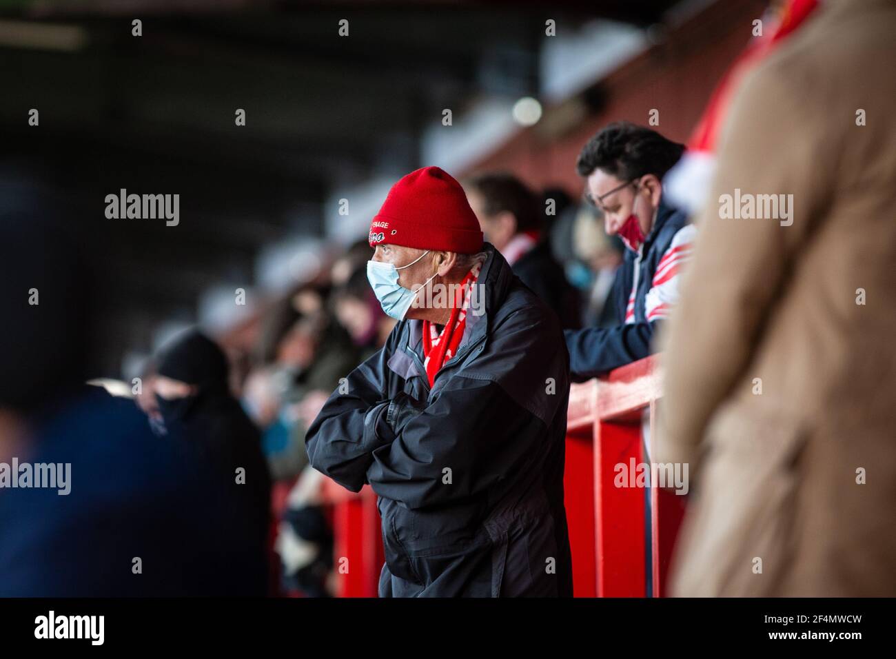 Les fans et les spectateurs regardent le match de football de la ligue inférieure pendant Covid-19, pandémie du coronavirus en Angleterre, au Royaume-Uni. Porter des revêtements de visage et des masques de visage. Banque D'Images
