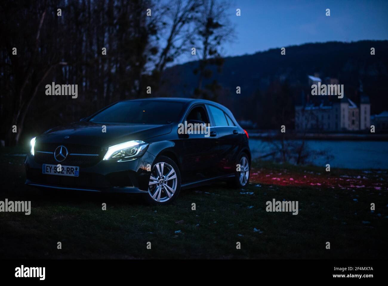 Photo nocturne d'une voiture Mercedes Benz noire de luxe en face d'un vieux château près de Lyon, France. Banque D'Images