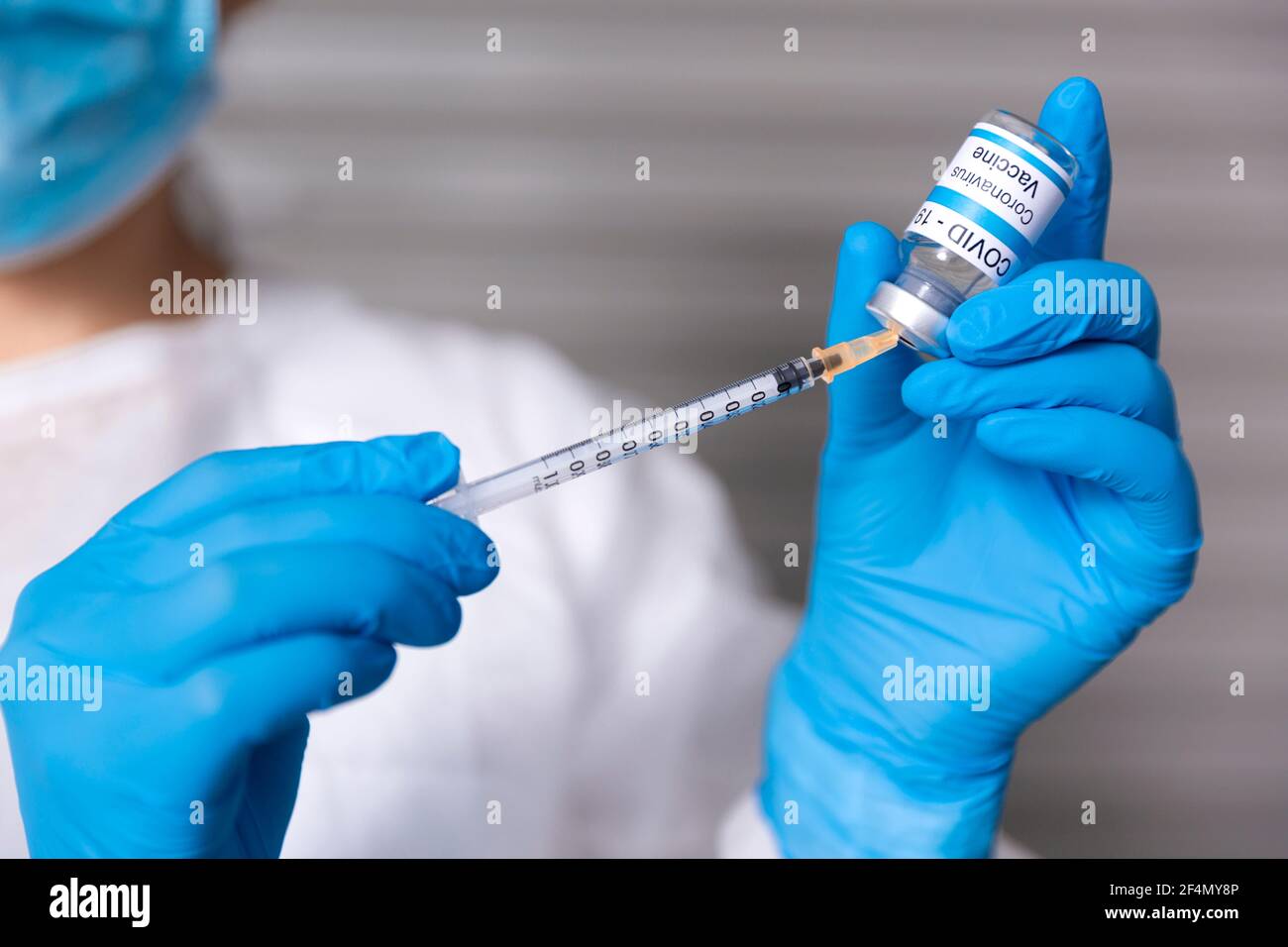 Gros plan du travailleur de la santé qui prépare une dose pour injection du vaccin Covid-19. Elle porte un masque médical et des gants de protection et porte un Banque D'Images