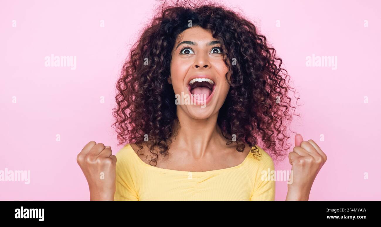 jeune femme émerveillement célébrant le triomphe isolée sur rose Banque D'Images