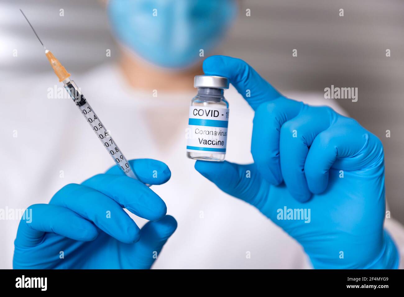 Gros plan d'un professionnel de la santé portant un masque médical et des gants de protection portant une seringue et un flacon en verre de vaccin Covid-19. Coronavirus vacciné Banque D'Images