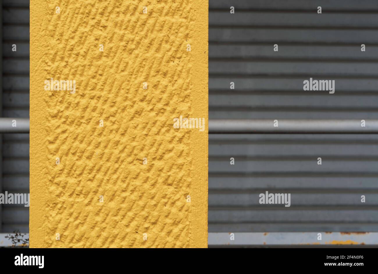 Fond en béton agréable ton jaune sur les volets gris fermés - Texture de la surface du mur - Grunge fond de couleur lumineuse dans gris urbain Banque D'Images