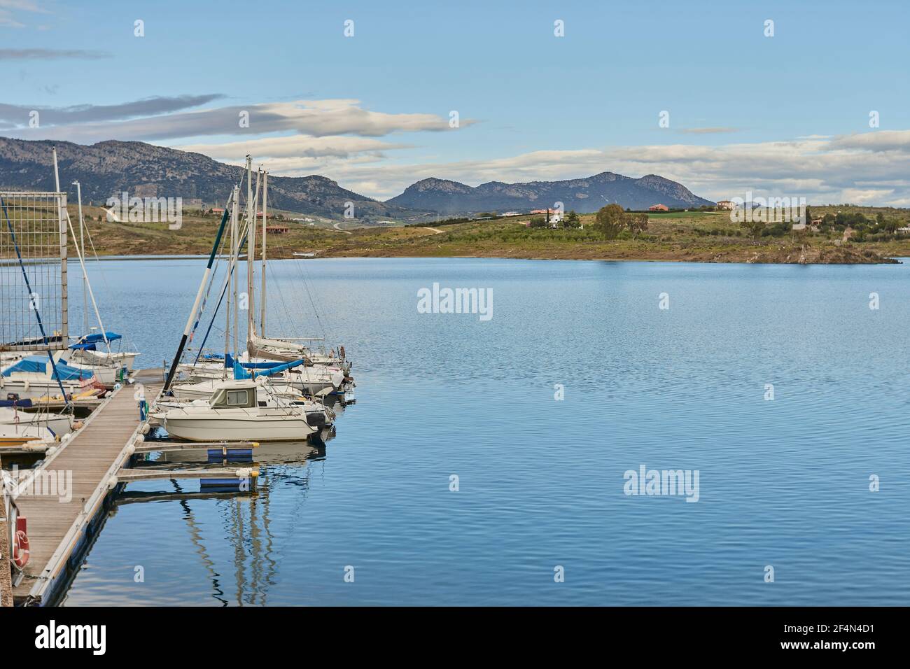 Bateaux amarrés dans une petite marina avec des eaux calmes et montagnes en arrière-plan Banque D'Images