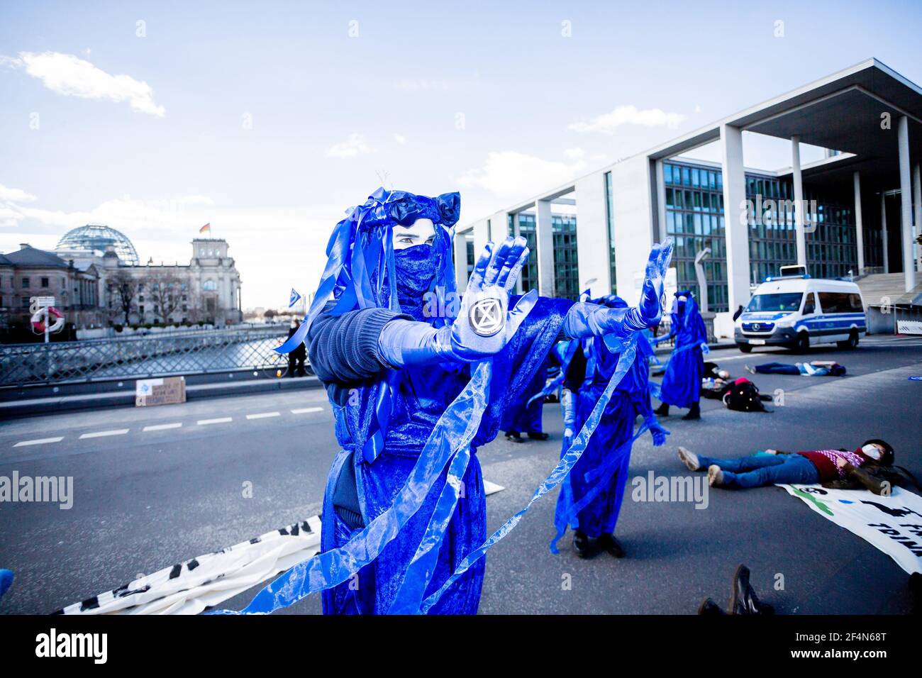 Berlin, Allemagne. 22 mars 2021. Des personnes vêtues de « rebelles bleus » se tiennent sur le pont Marschall lors d'une représentation du mouvement de protection de l'environnement « rébellion d'extinction » à l'occasion de la Journée mondiale de l'eau sous la devise « protéger l'eau - arrêter la fracturation dans le monde entier » ; le bâtiment Reichstag peut être vu en arrière-plan. Credit: Christoph Soeder/dpa/Alay Live News Banque D'Images