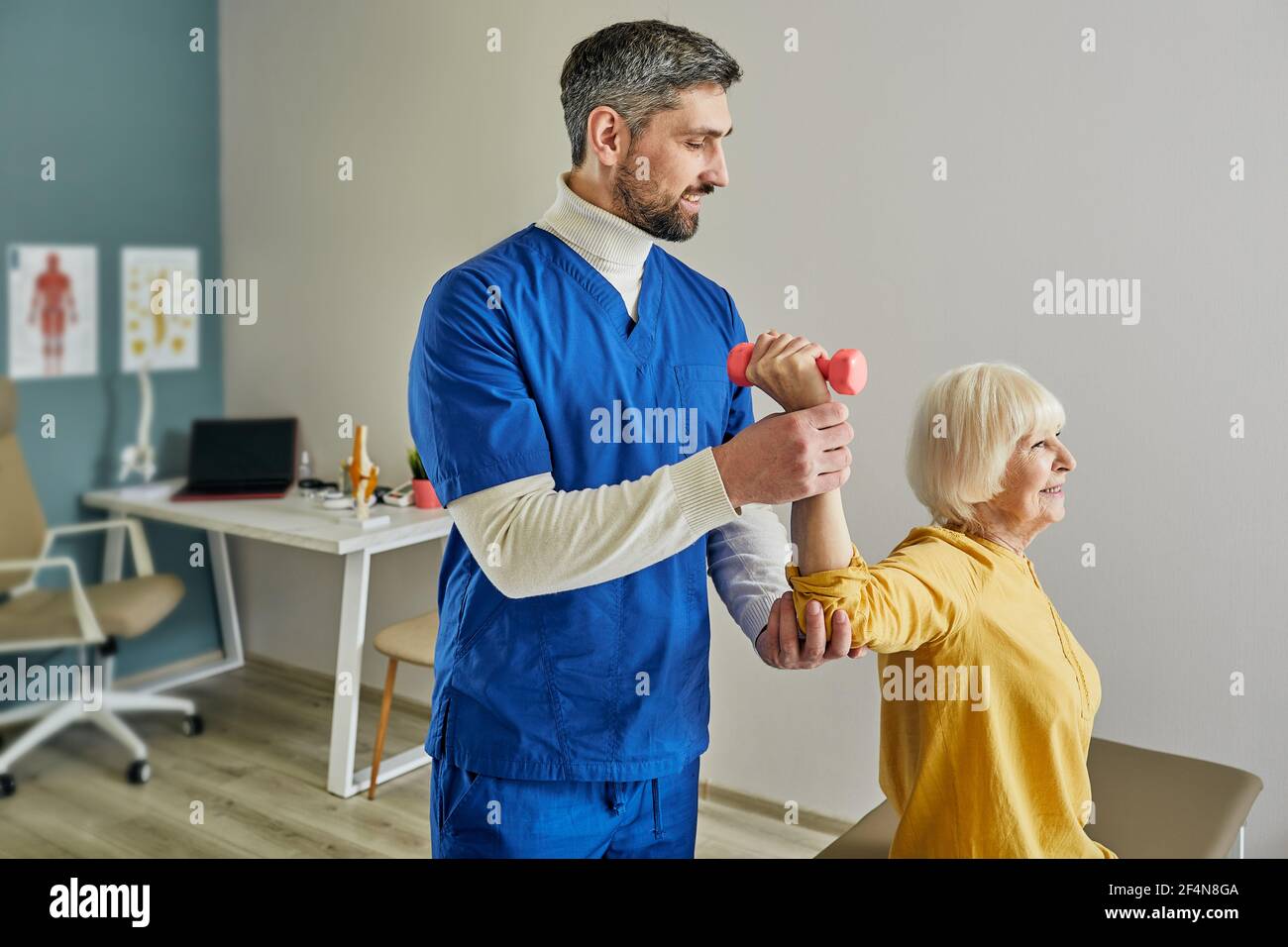 Une femme plus âgée s'entraîne avec un physiothérapeute utilisant des haltères à un médecin centre Banque D'Images