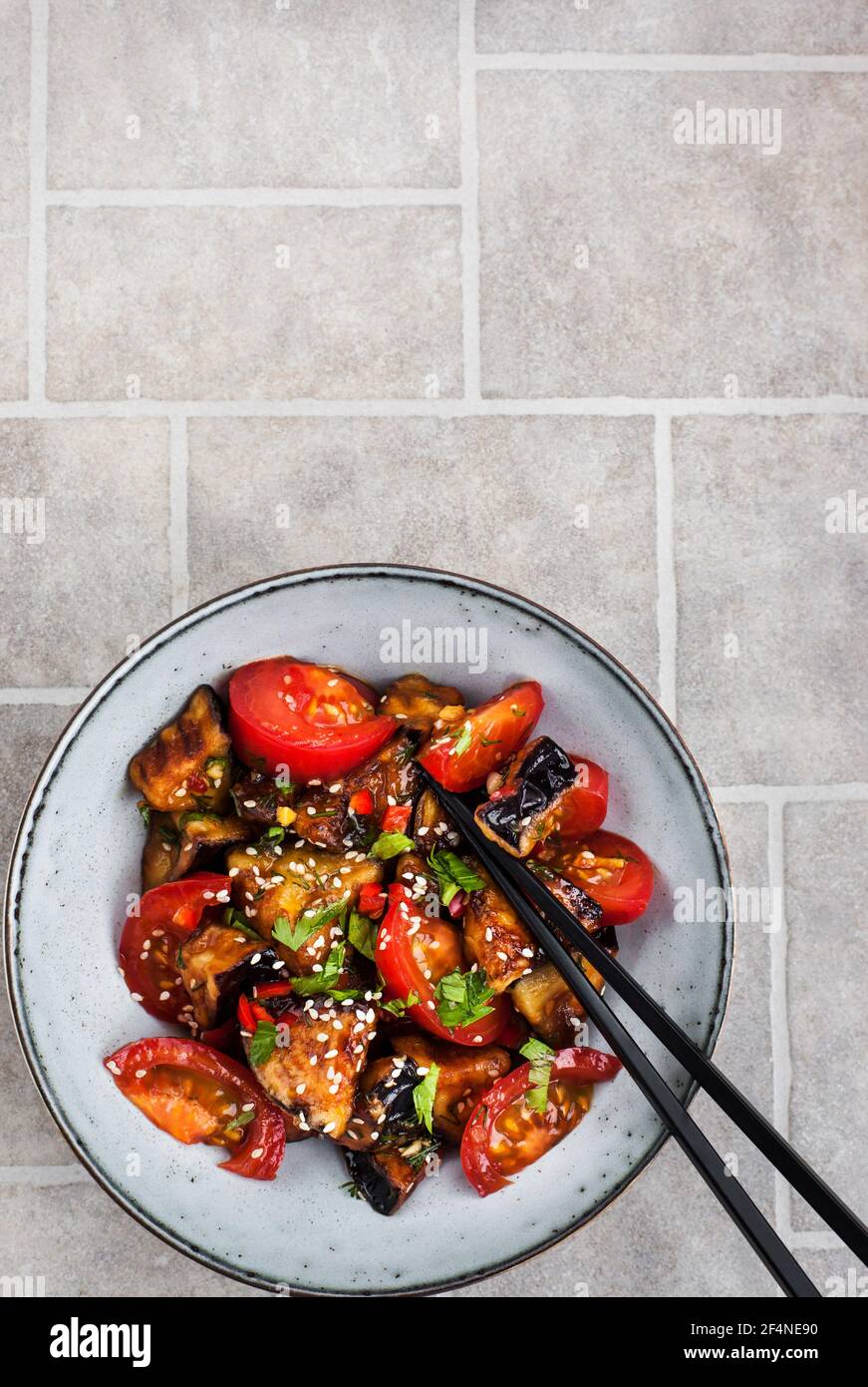 Gros plan sur le sauté d'aubergines de style chinois avec sésame, piment et tomates, vue du dessus, espace pour les copies Banque D'Images