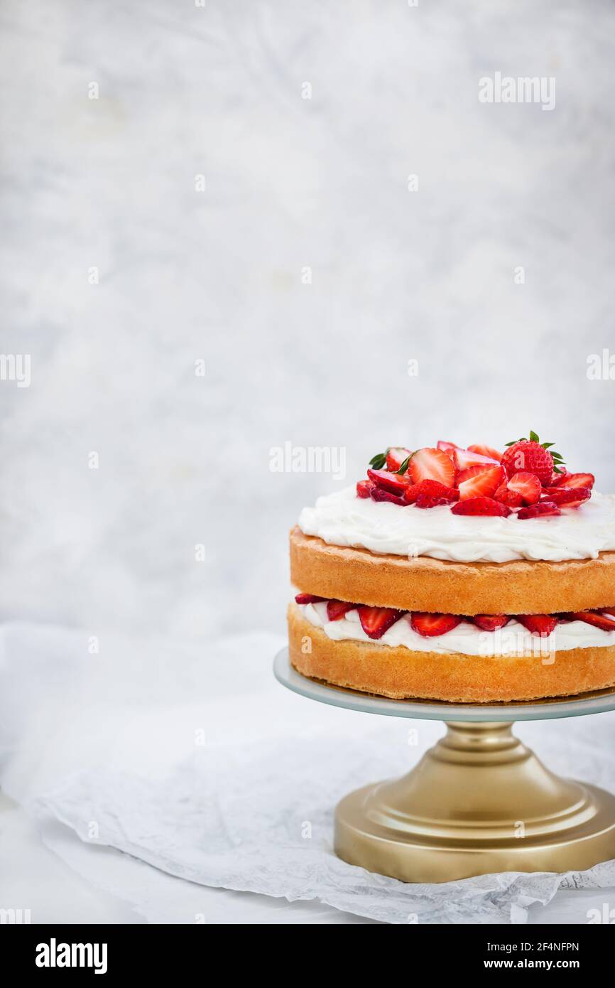 Gâteau éponge Victoria, délicieux gâteau à la vanille maison décoré de crème fouettée et de fraises fraîches, sur blanc Banque D'Images