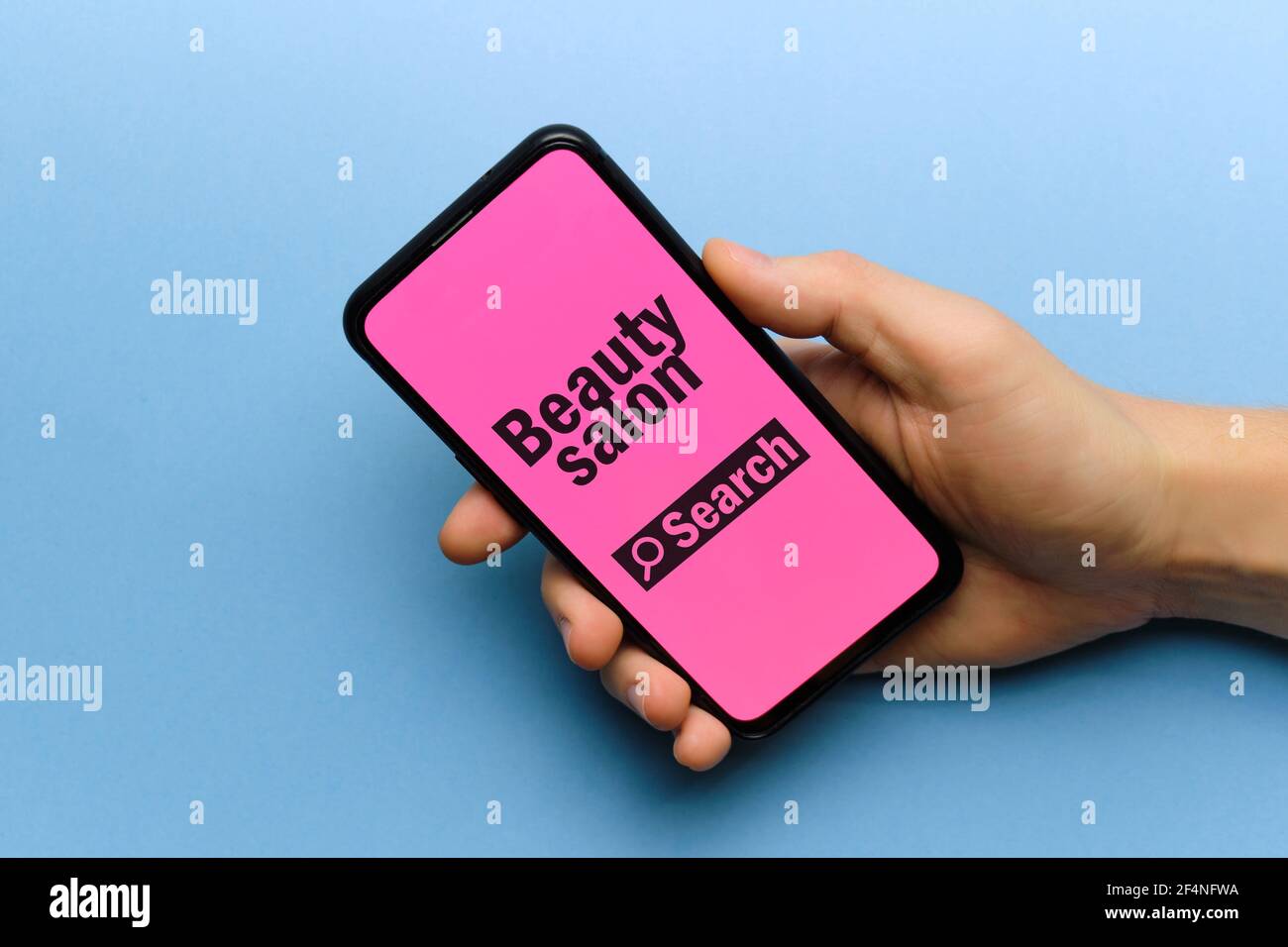 Personne tenant le smartphone à la main avec le concept de recherche de salon de beauté. Banque D'Images