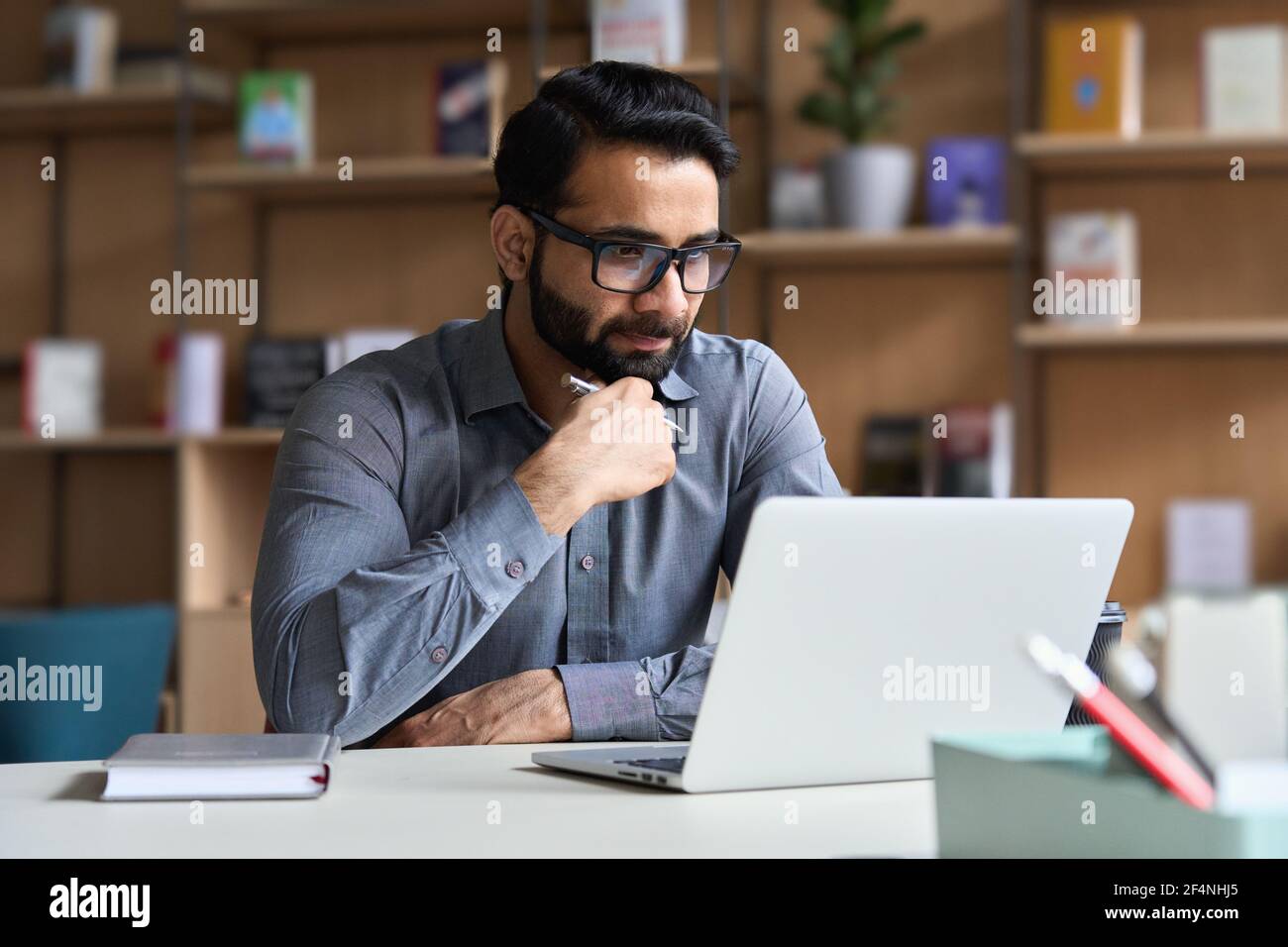 Homme d'affaires indien sérieux travaillant ou étudiant sur un ordinateur portable. Banque D'Images