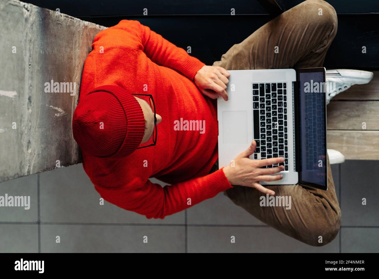 Indépendant homme assis sur le banc à côté de jambes de fenêtre croisées, travail en ligne sur ordinateur portable. Travail à distance Banque D'Images