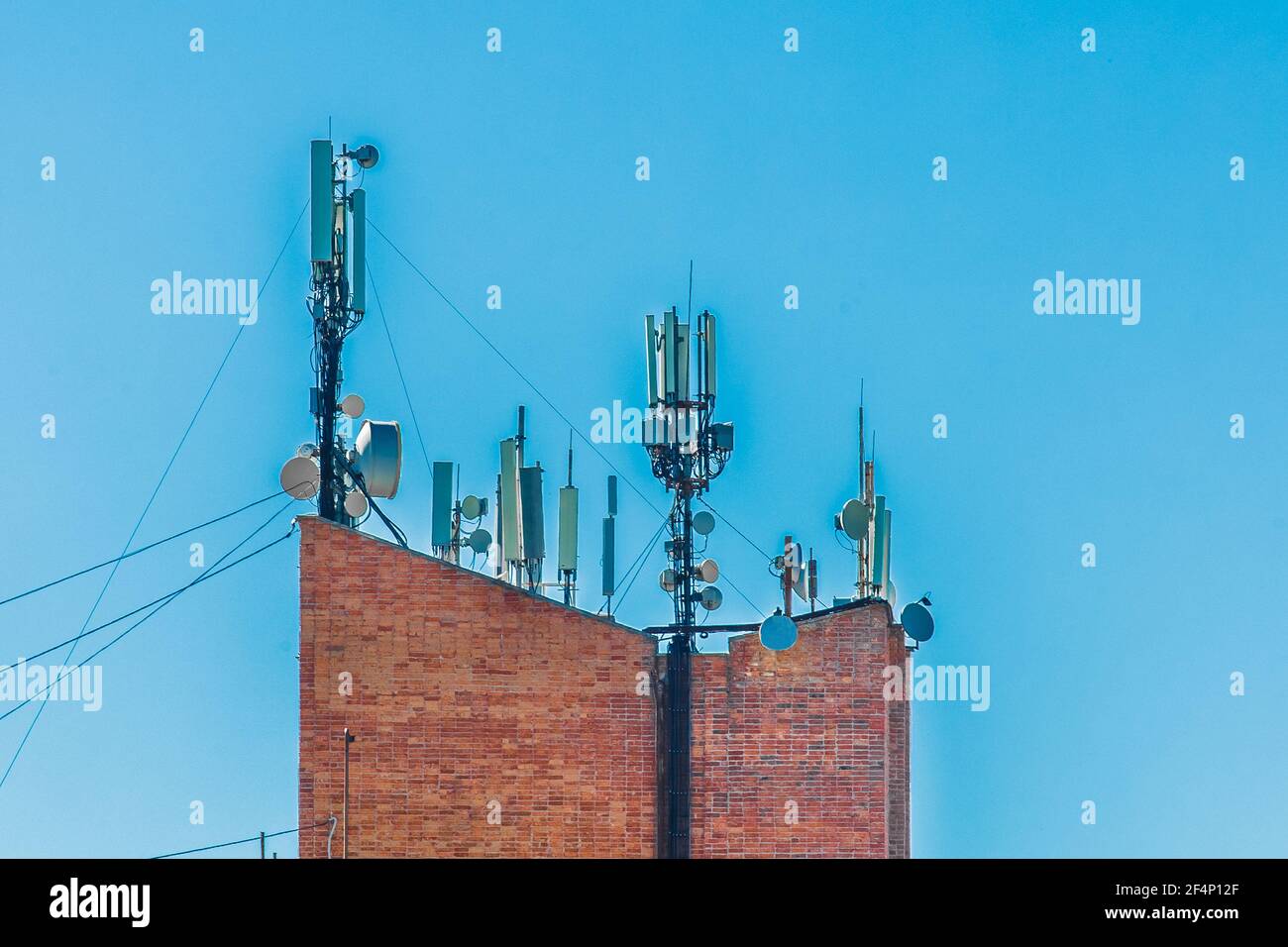 Tour de brique de télécommunication avec antennes sans fil mobiles sur fond bleu ciel. Banque D'Images