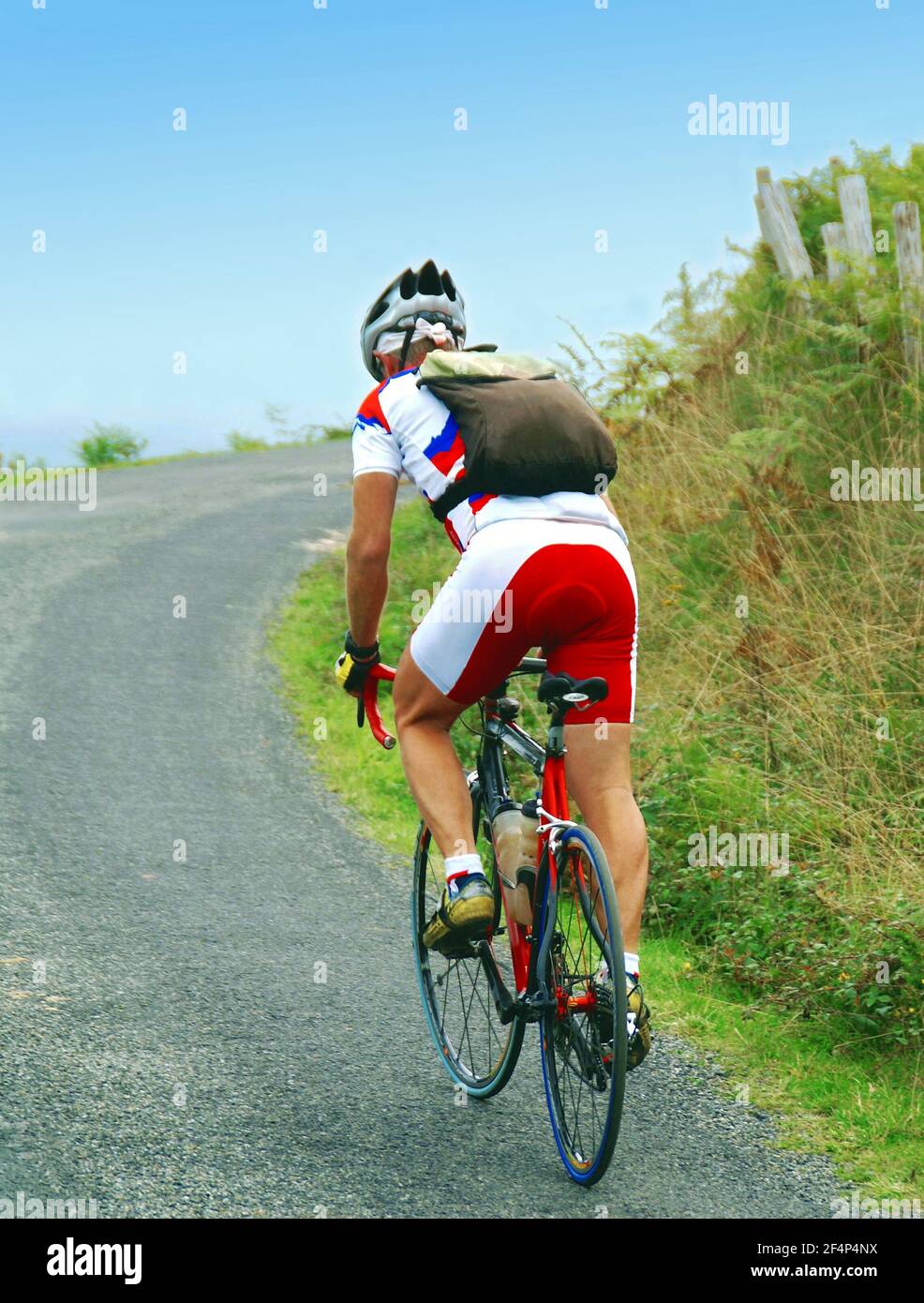 Cycliste sur une route de montagne sur fond de ciel bleu. Banque D'Images