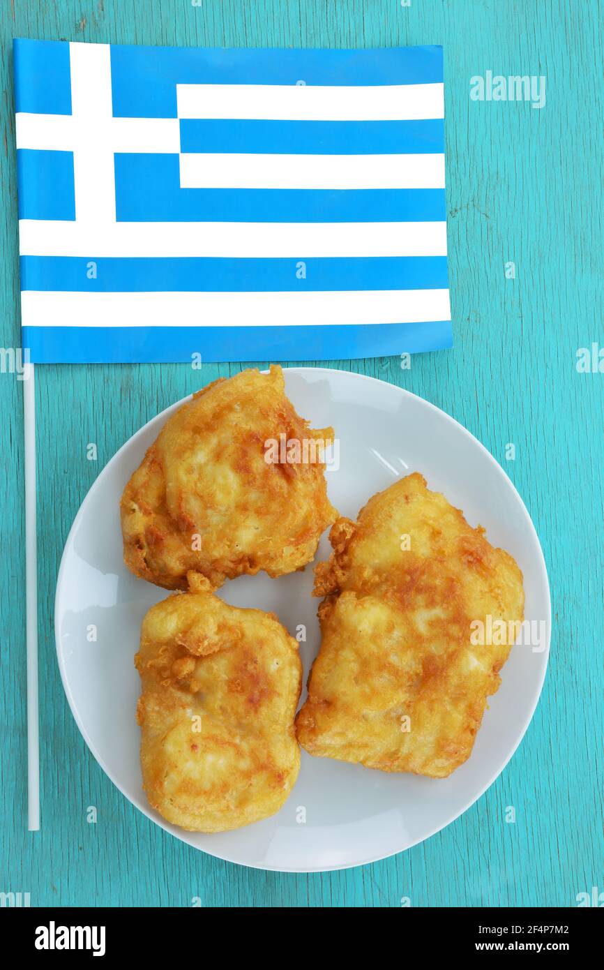 Morceaux de pain écroulés de morue et drapeau grec table turquoise Banque D'Images