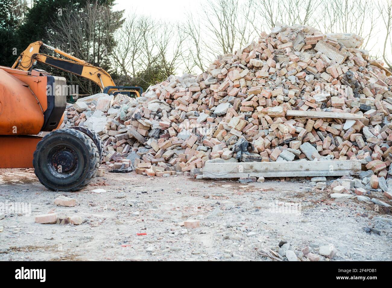 La pelle élimine les déchets de construction après la démolition de bâtiments. Construction de gravats, briques, pierres. Courrier indésirable, déchets accumulés. Scène de rue. Recyclage Banque D'Images