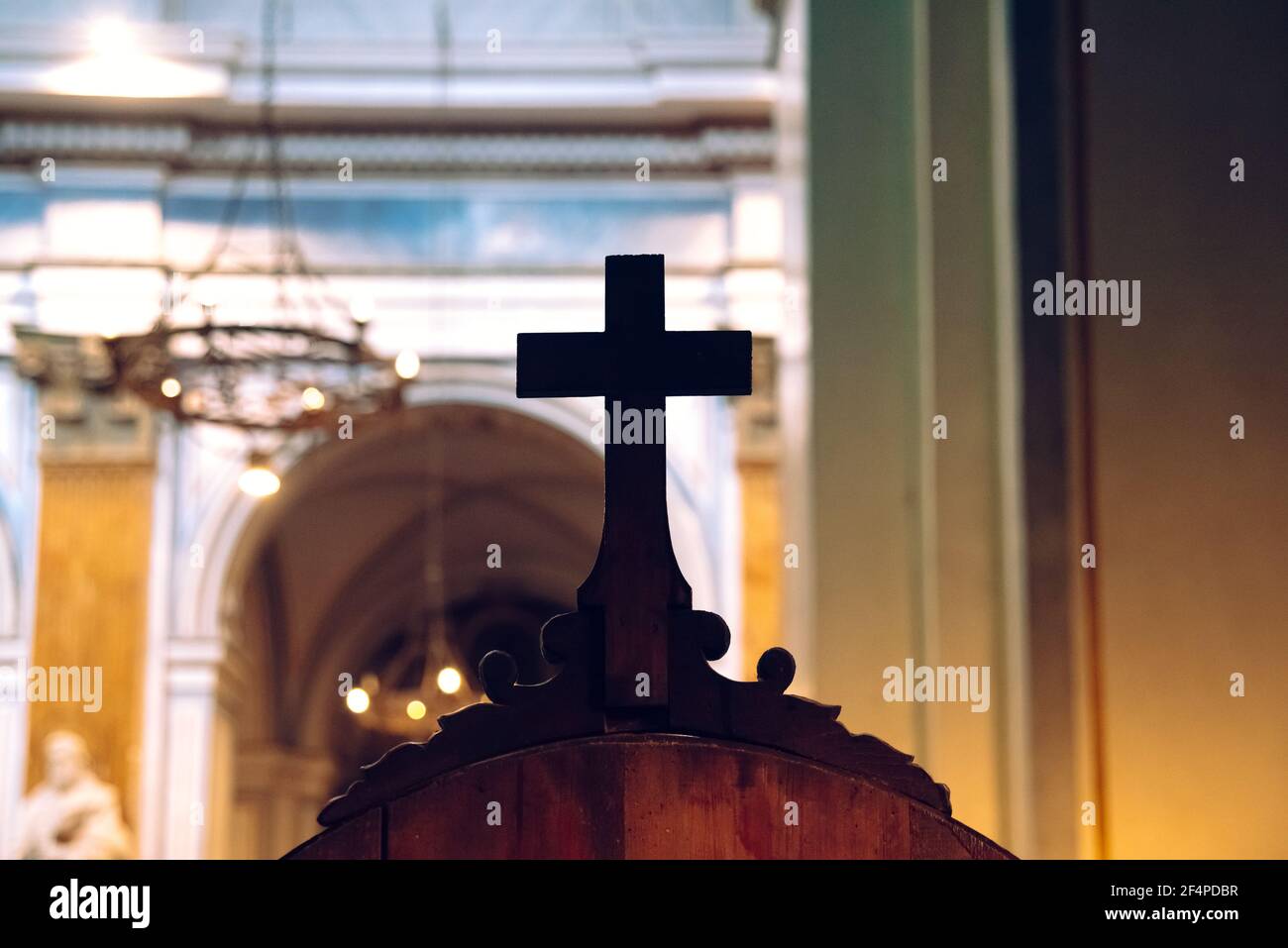 Croix religieuse en bois sur un confessionnel dans l'intérieur sombre d'une église catholique, avec un arrière-plan hors foyer. Banque D'Images