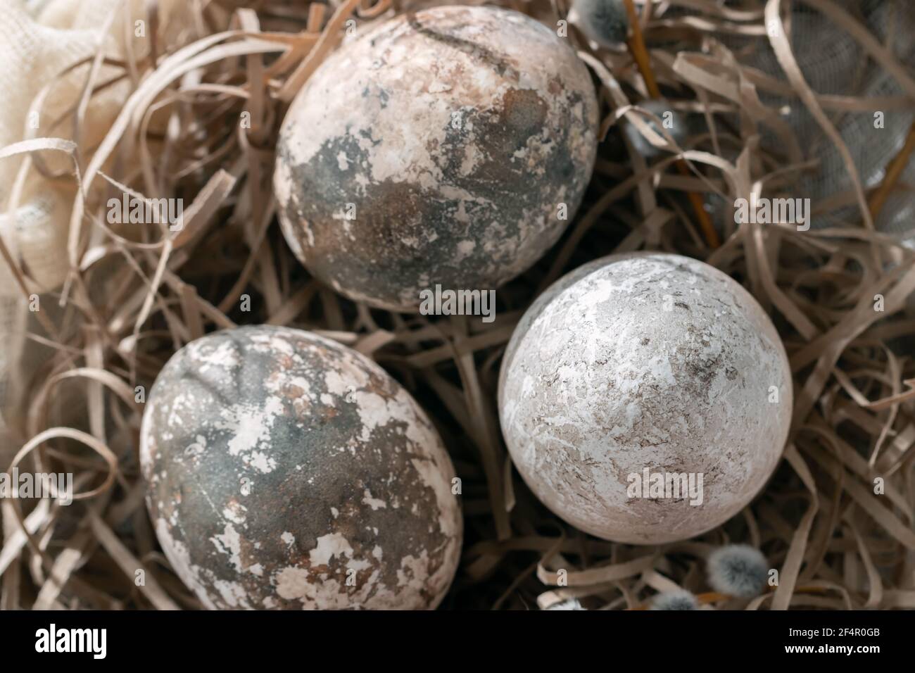 Composition Pâques - plusieurs œufs en marbre peints avec des teintures naturelles dans un nid en papier sur la table, vue du dessus Banque D'Images