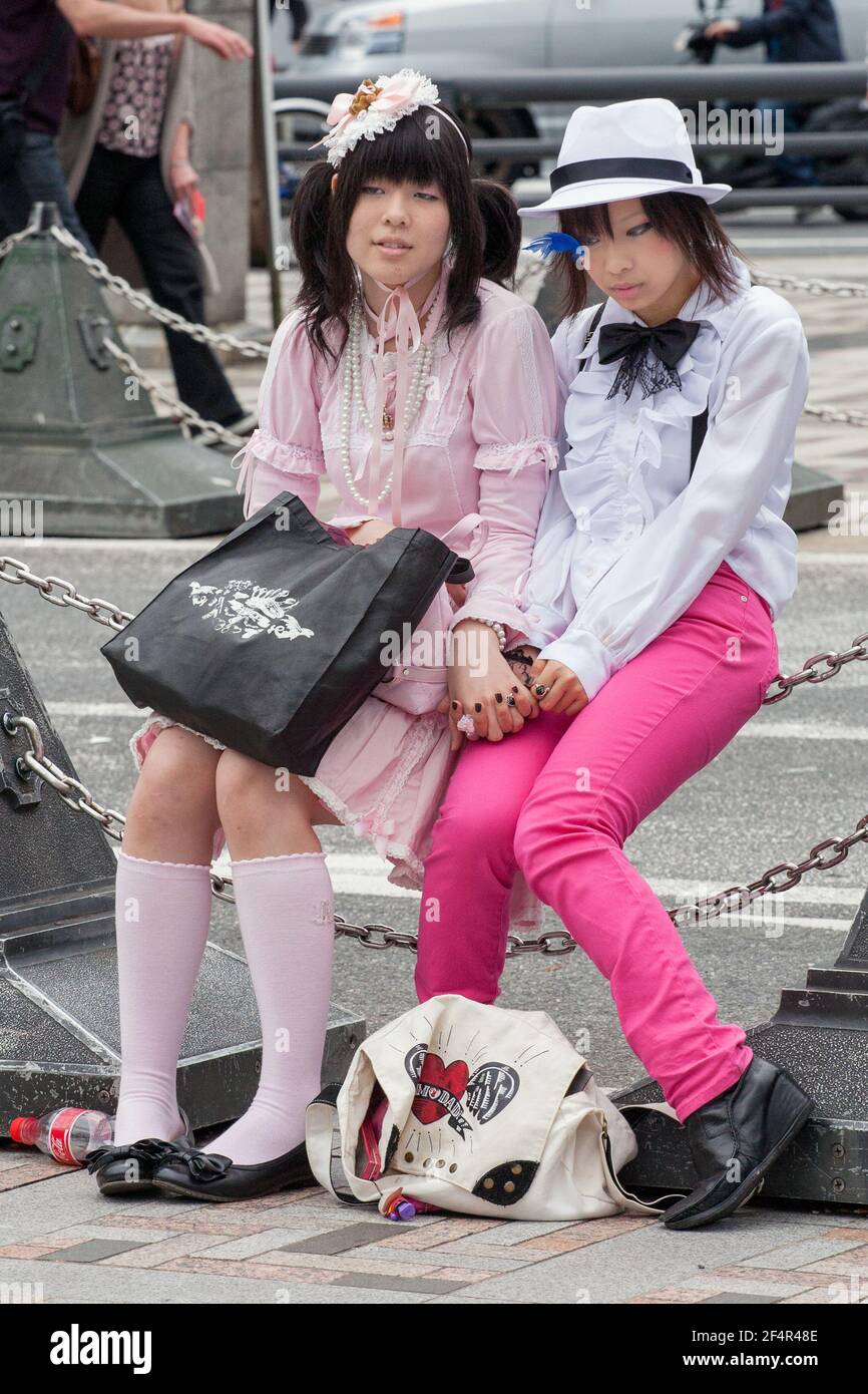 Deux jolies filles japonaises vêtues de main assise sur une clôture enchaînée à Harajuku, Tokyo, Japon Banque D'Images