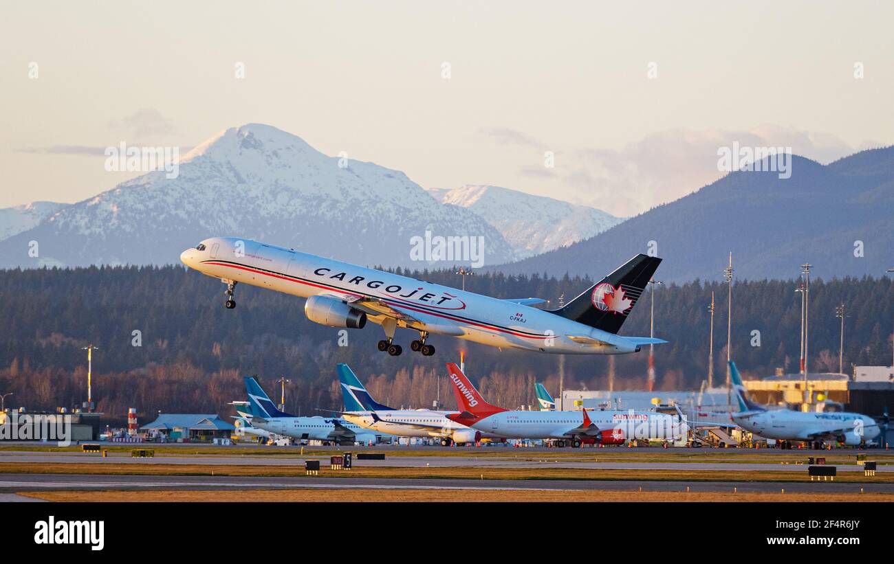 Richmond, Colombie-Britannique, Canada. 22 mars 2021. Un avion Cargojet Boeing 757 (C-FKAJ) prend son envol au coucher du soleil depuis l'aéroport international de Vancouver. En arrière-plan, les avions de ligne WestJet et Sunwing Boeing 737 se sont garés au terminal intérieur de l'aéroport. Crédit : Bayne Stanley/ZUMA Wire/Alay Live News Banque D'Images