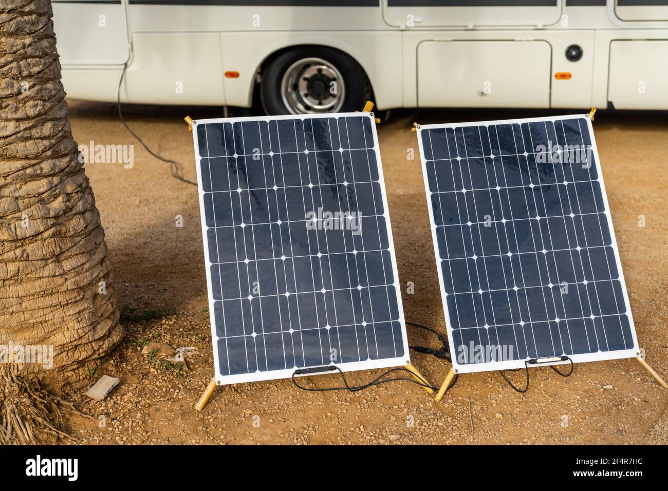 Deux panneaux solaires mobiles à côté d'un palmier avec Un grand camping-car derrière Banque D'Images