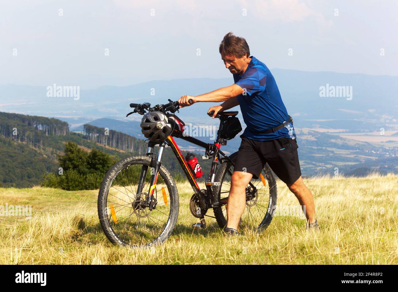 Homme marchant avec le vélo, Homme poussant un vélo de montagne en montée Banque D'Images