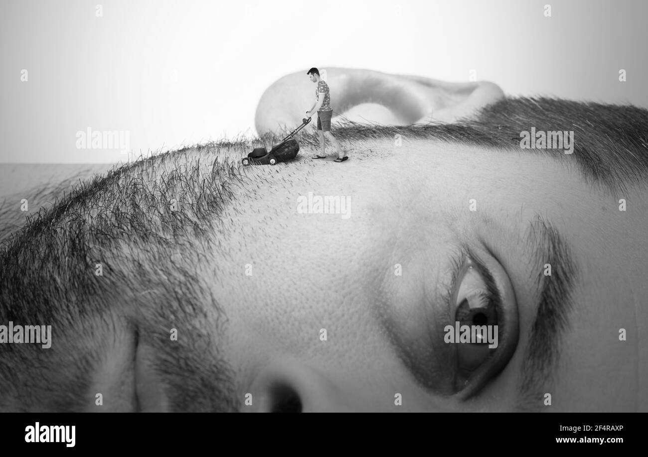 Homme équipé d'une tondeuse à gazon miniature se raser son visage géant, concept d'entretien Banque D'Images