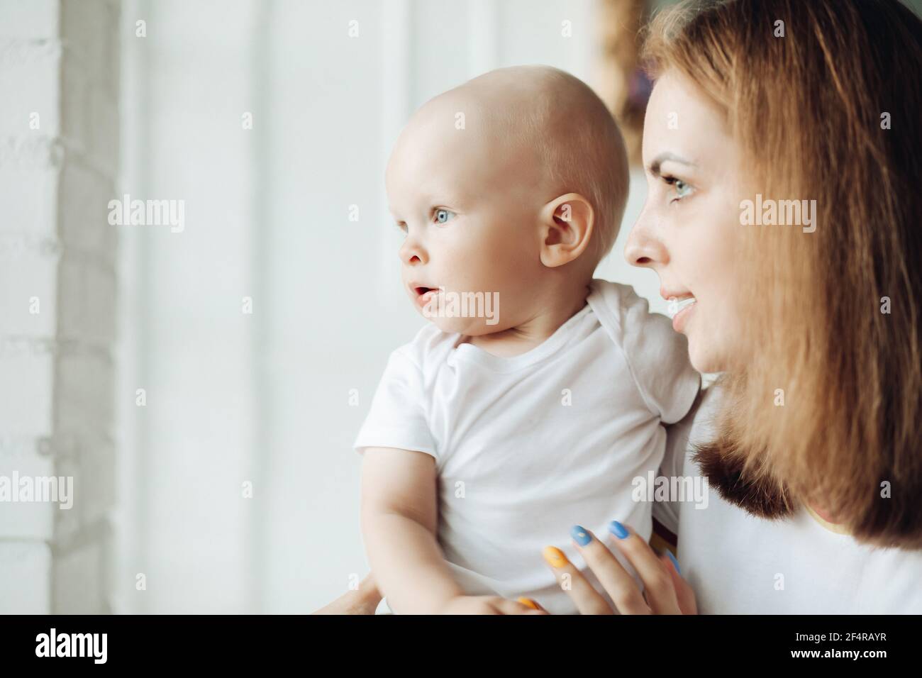 Joli bébé et sa mère près de la fenêtre. Banque D'Images