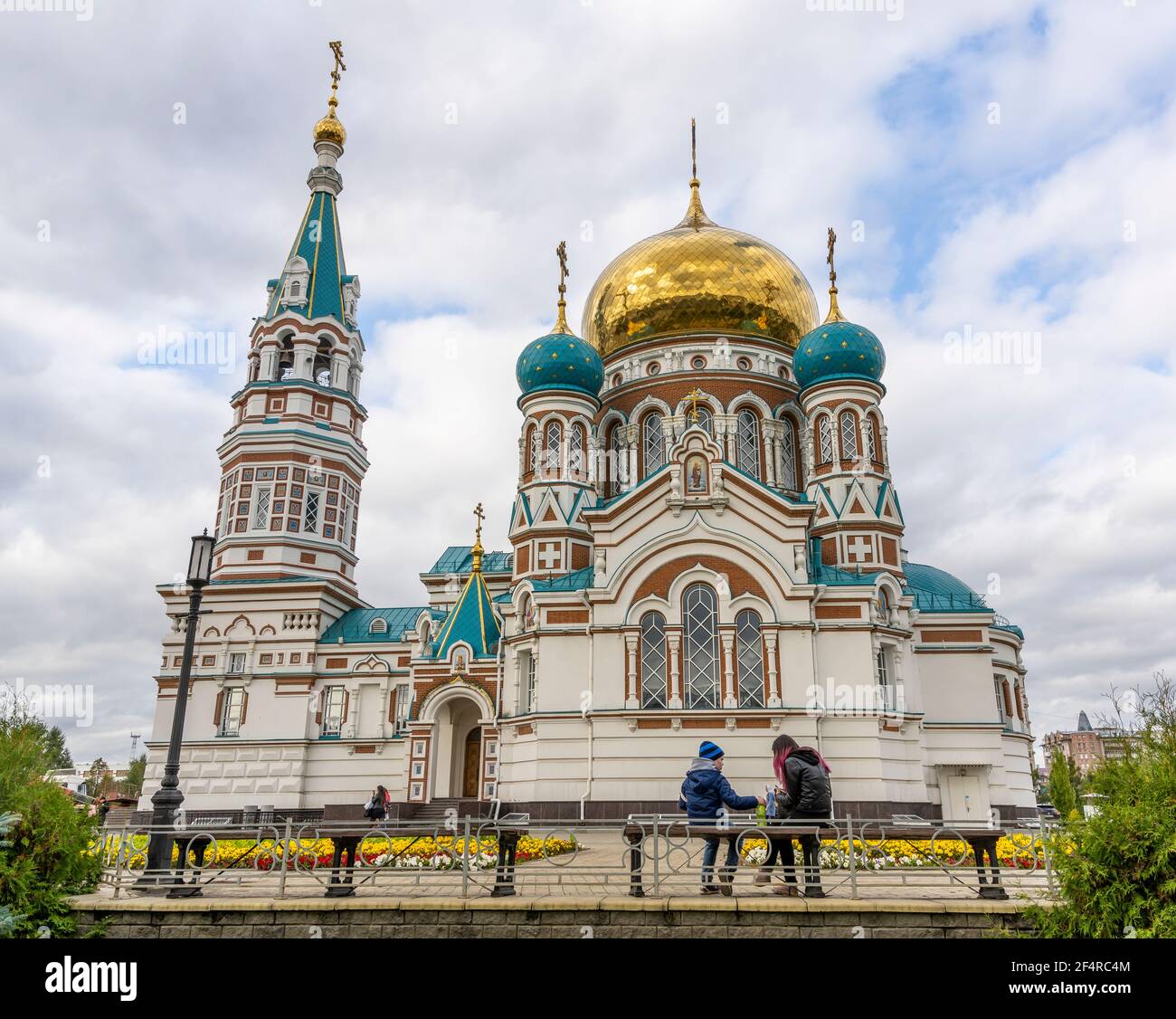 Omsk, Russie - 13 septembre 2019 : Cathédrale de Dormition à Omsk avec deux personnes ou enfants assis devant l'église, Sibérie, Russie. Banque D'Images