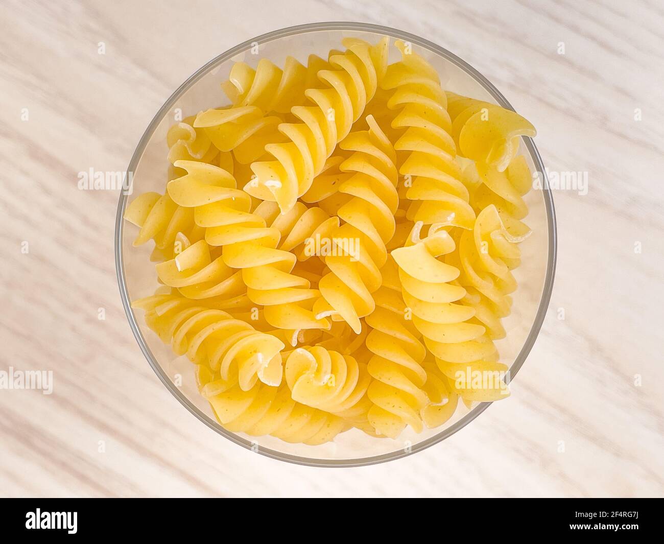 Pâtes italiennes sèches en forme de spirale en verre sur table en bois dans la cuisine. La nourriture. Macaroni non cuit Banque D'Images