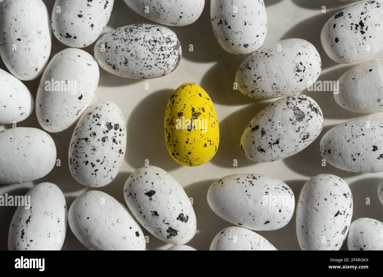 Petits oeufs blancs de Pâques et un oeuf jaune au milieu, avec des éléments noirs, fond de pâques Banque D'Images