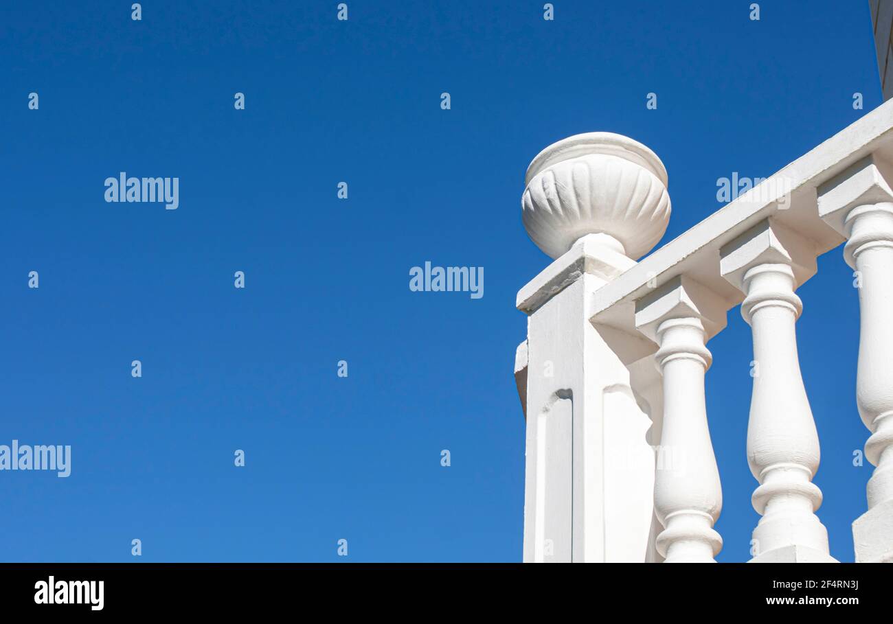 Balustrade blanche baignée de soleil sur fond bleu ciel. Montant fini avec jardinière décorative en béton Banque D'Images