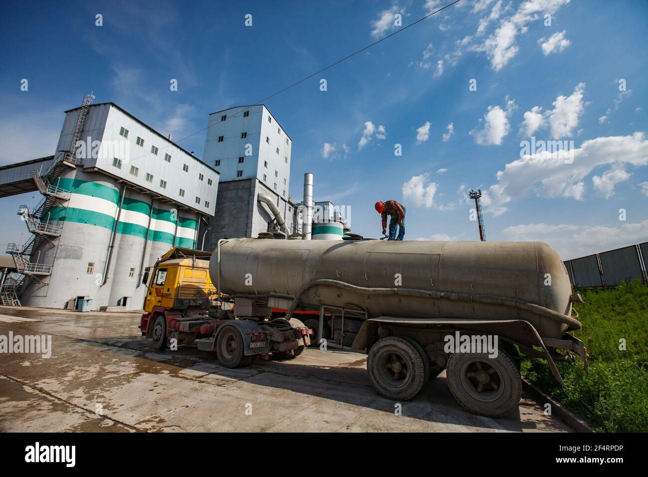 Usine de ciment standard. Silos en béton et bâtiments industriels. Chariot de ciment avec ouvrier au premier plan. Vue panoramique. Banque D'Images