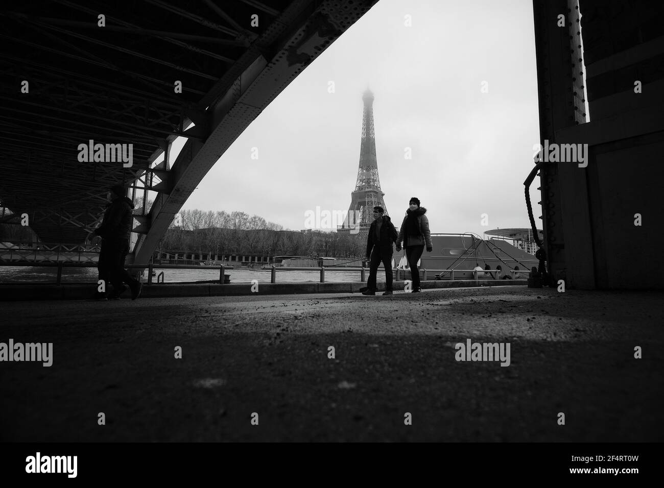 Paris, France - 31 janvier 2021 : UN couple portant des masques, marchant sous un pont près de la tour Eiffel à Paris, en noir et blanc Banque D'Images
