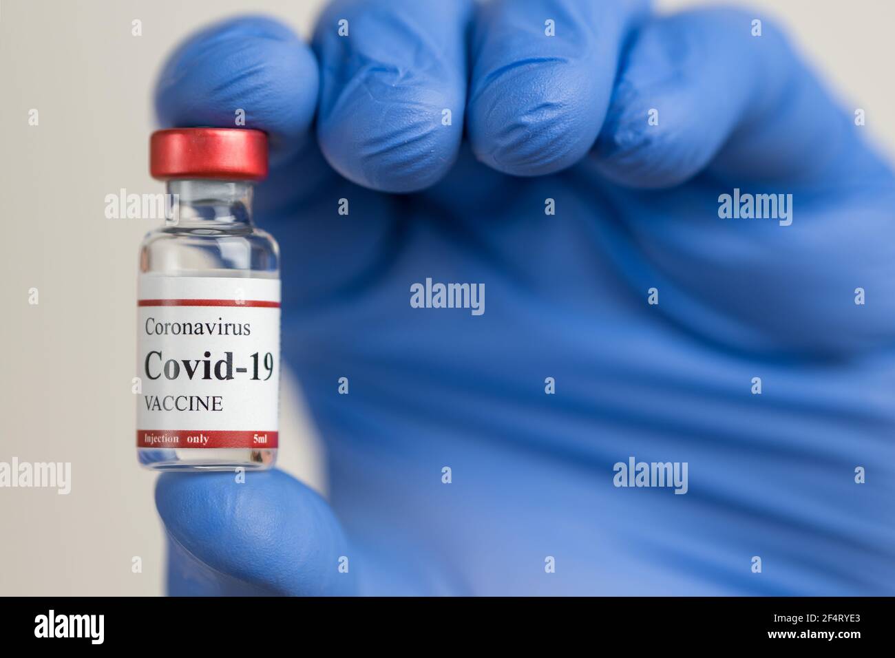 Les médecins passent des gants bleus en latex et maintiennent le flacon de vaccin contre le coronavirus Covid-19. Banque D'Images