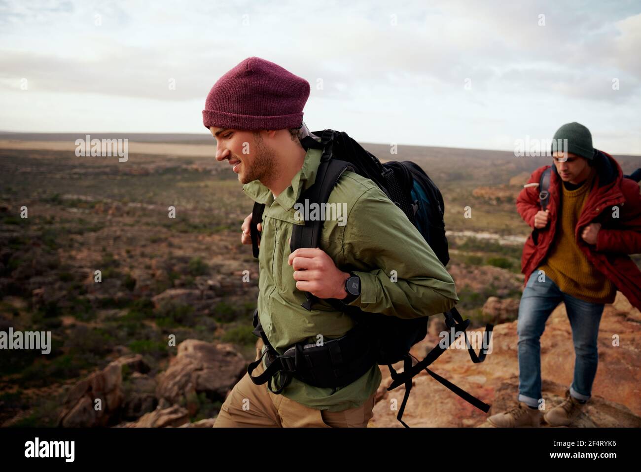 Deux amis mâles avec sac à dos et montagne d'escalade de casquette d'hiver Banque D'Images