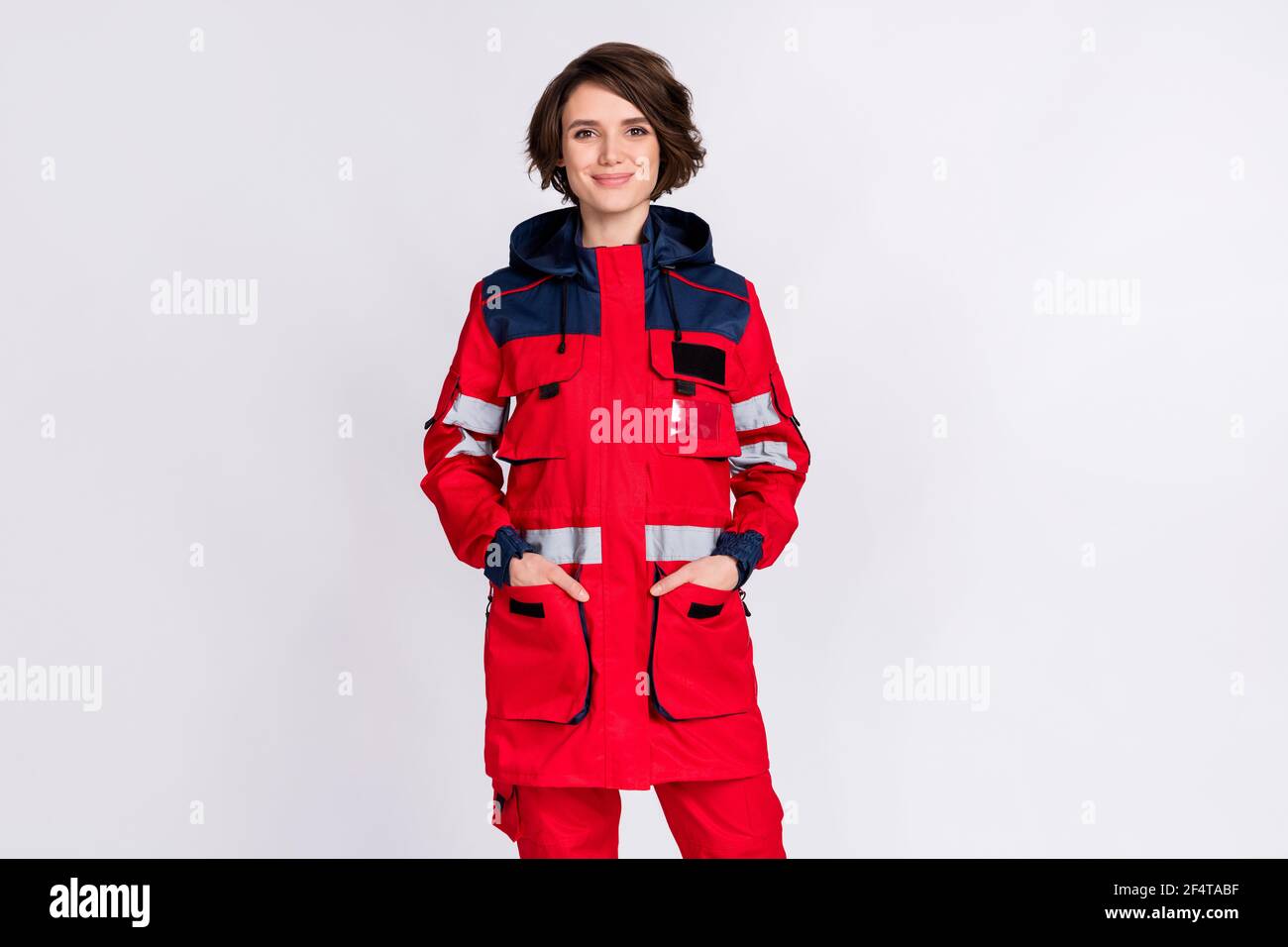 Photo d'optimiste belle brune dame stand porter uniforme isolé sur fond gris Banque D'Images