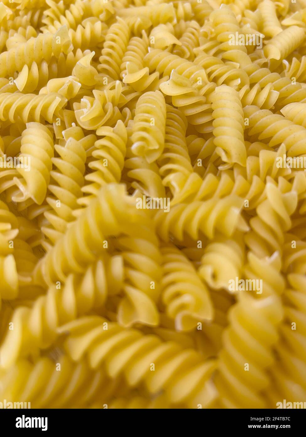 Fond ou texture de la nourriture pâtes italiennes sèches crues en forme de spirale. Gros plan, macro, vue de dessus. Macaroni non cuit Banque D'Images