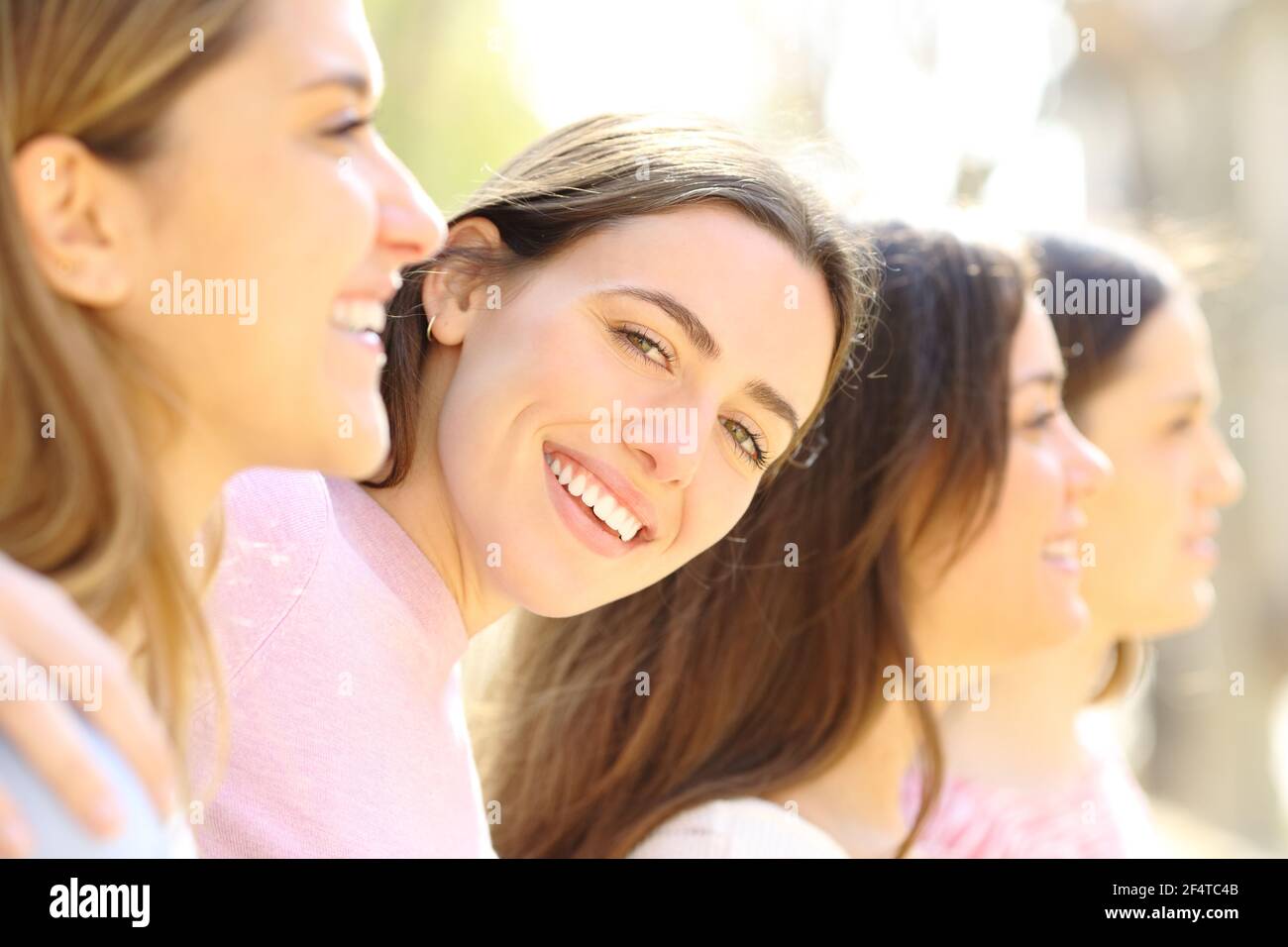 Une femme heureuse avec un sourire parfait se posant entre ses amis la rue un jour ensoleillé Banque D'Images