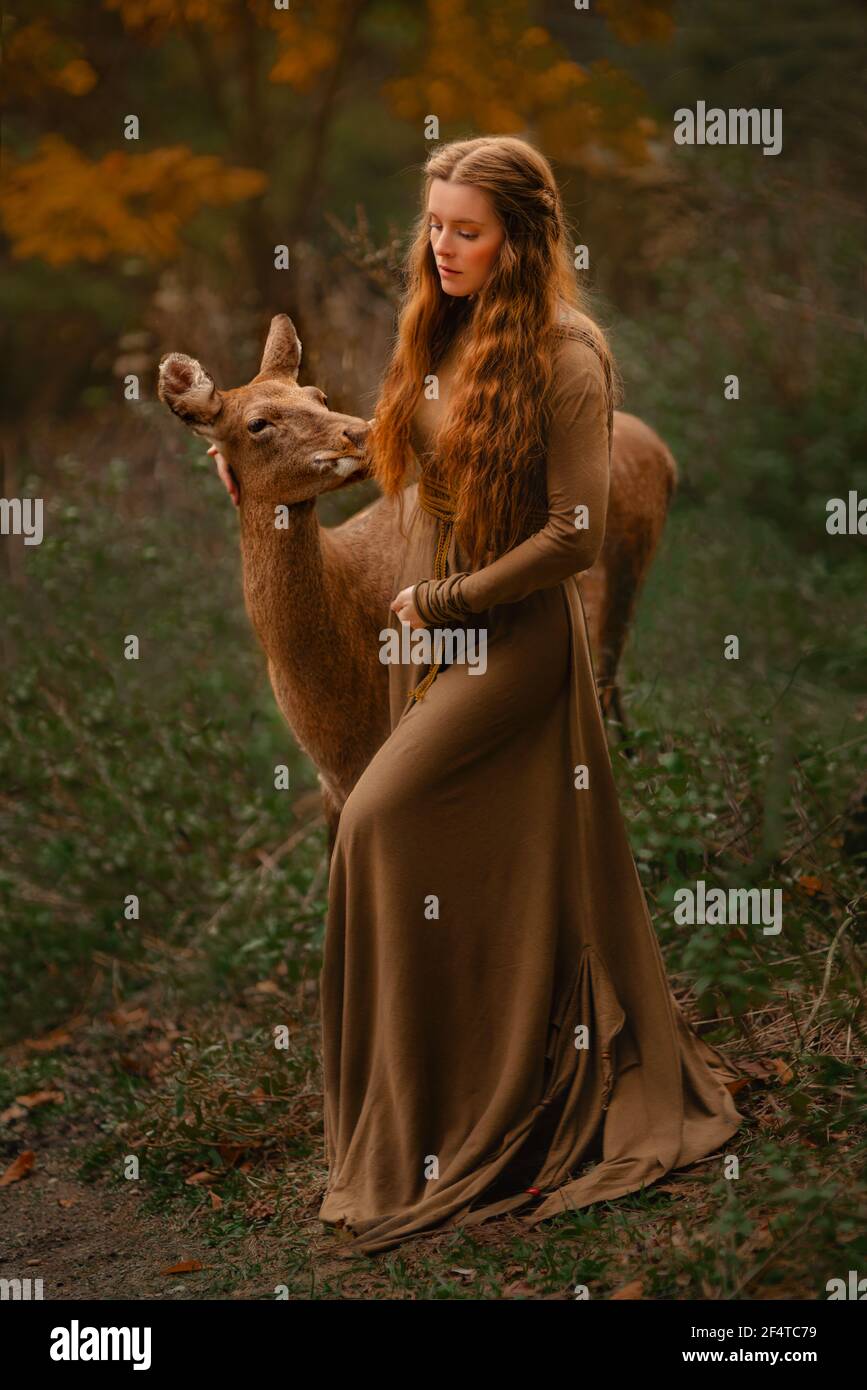Fille REDHEAD avec cerf dans une longue robe Banque D'Images