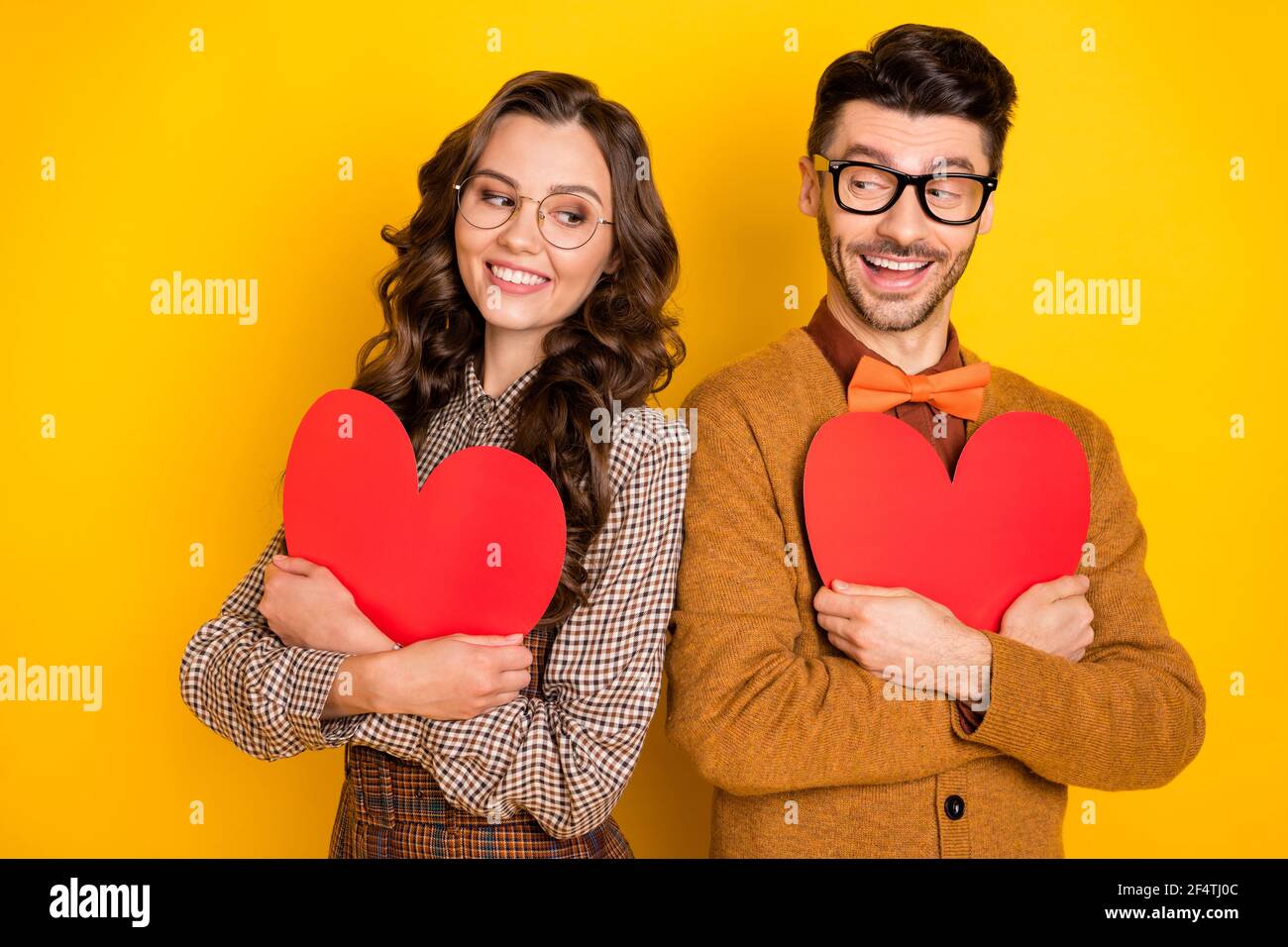 Portrait d'amis joyeux et séduisants couple d'amitié embrassant le cœur soi-même concept cupidon isolé sur fond jaune vif Banque D'Images