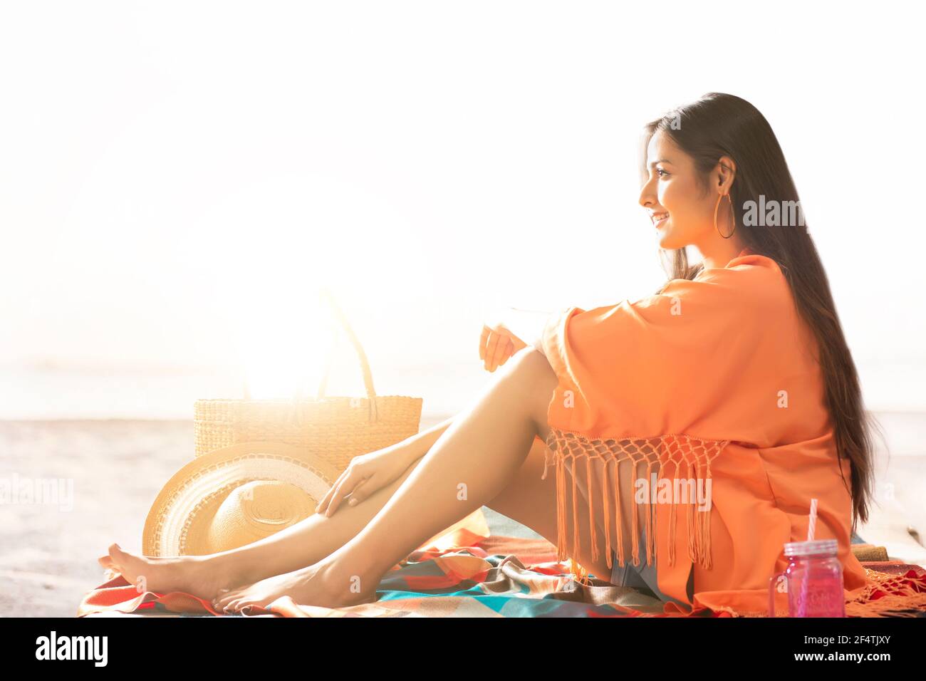 UNE JEUNE FEMME ASSISE SUR UNE PLAGE ET RELAXANTE Banque D'Images