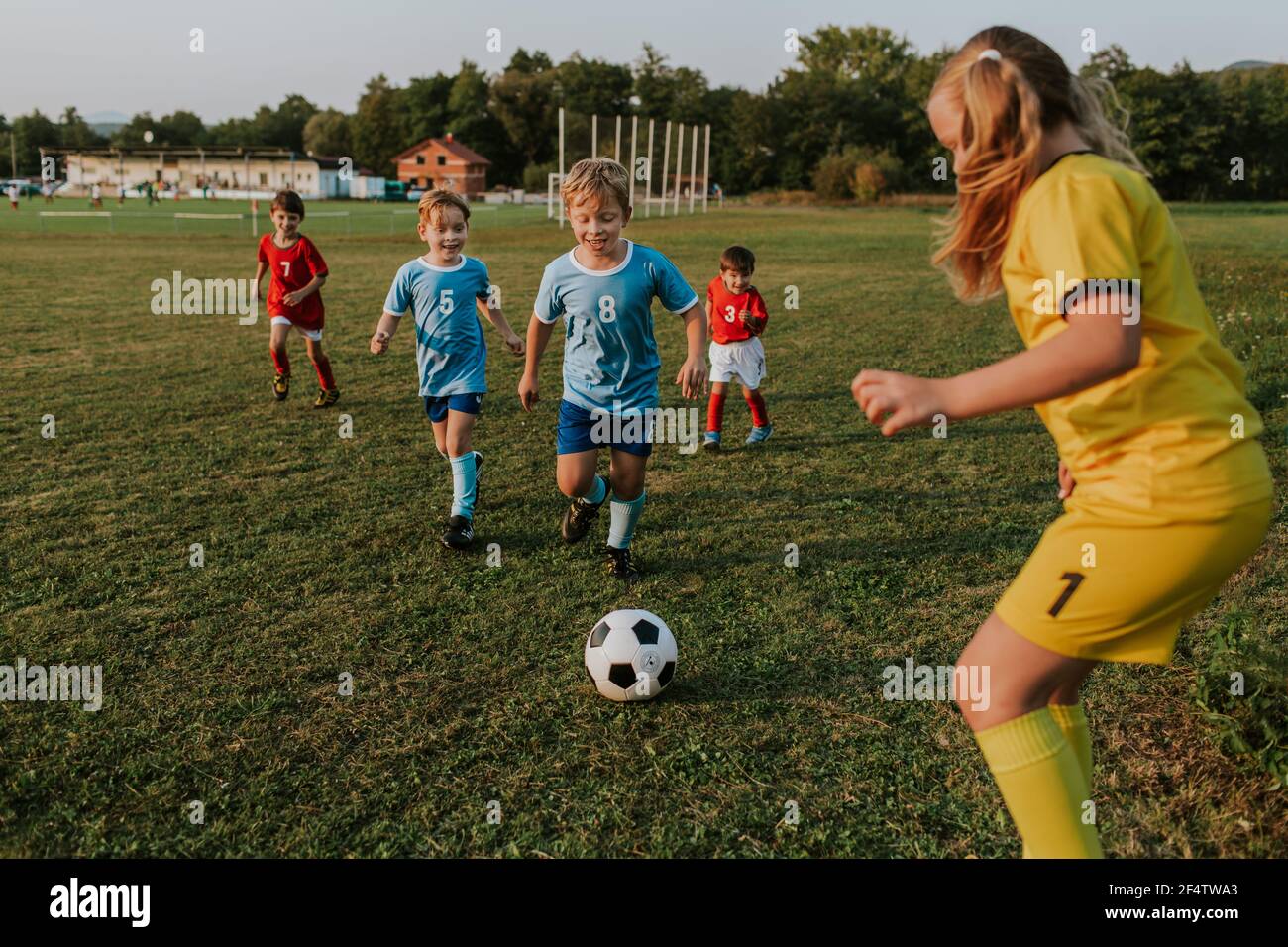 Enfants jouant au football à l'extérieur. Gardien de but de fille attrapant le ballon de football à la compétition amateur. Banque D'Images