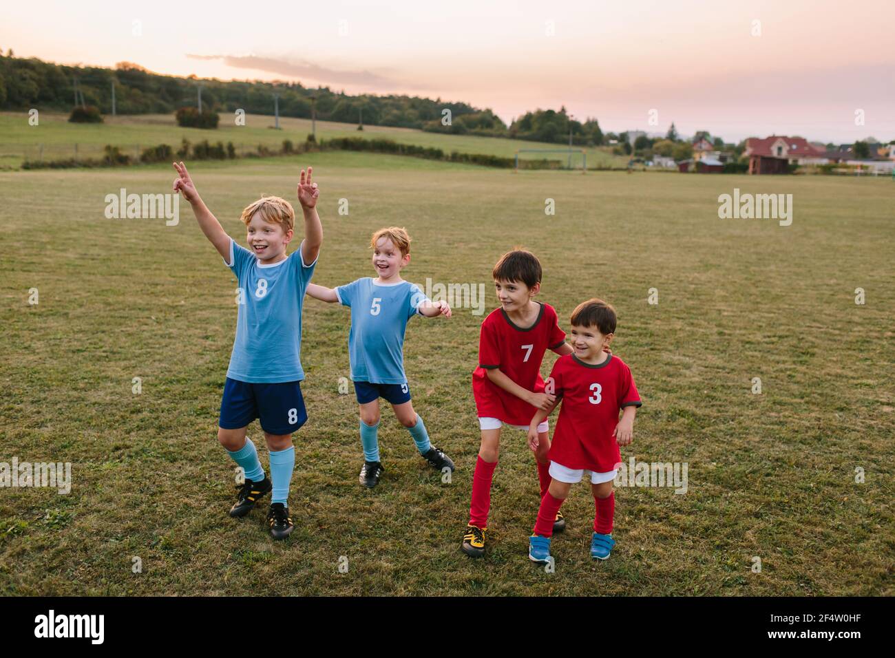 Enfants jouant au football amateur. Des garçons gais dans des robes de football ayant du plaisir à l'entraînement sur le terrain. Banque D'Images