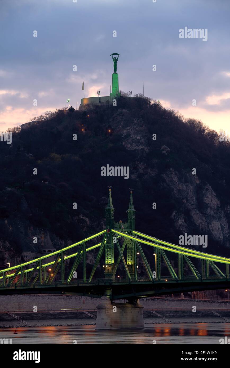 Vue unique sur le célèbre pont historique de la liberté et la statue de Budapest Hongrie. Décoration avec lumières vertes en raison de la fête du souvenir de St Patrick. Banque D'Images