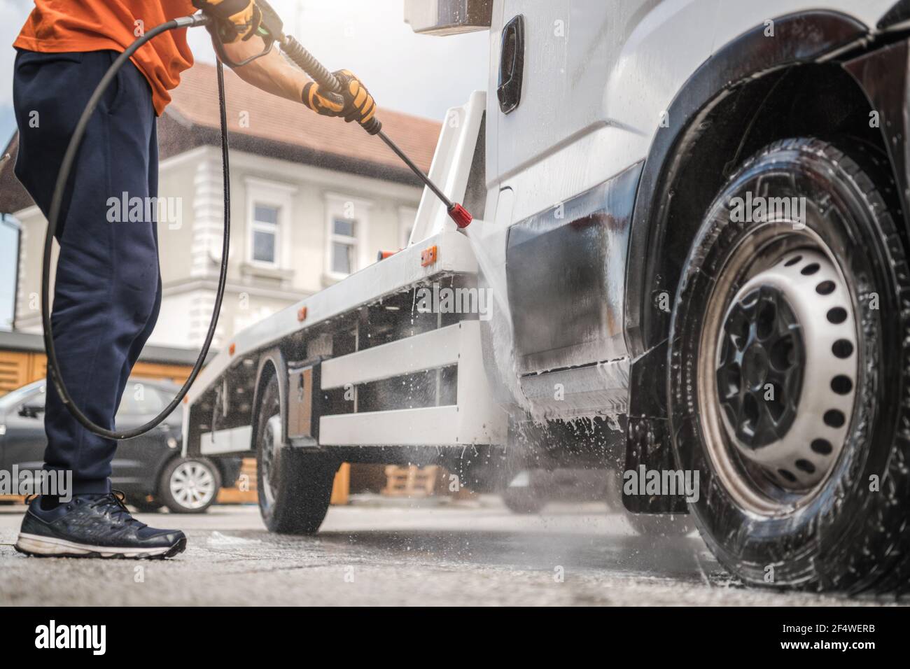 Travailleur caucasien dans son 40s Power Washing son camion de remorquage de véhicule commercial à l'intérieur de la voiture manuelle de lavage. Banque D'Images