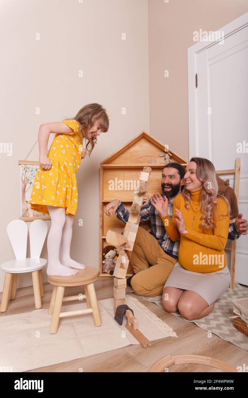 La famille attend un nouvel ajout. Une femme enceinte, son mari et sa fille  jouent ensemble dans la pépinière. Ils construisent une tour en bois bl  Photo Stock - Alamy